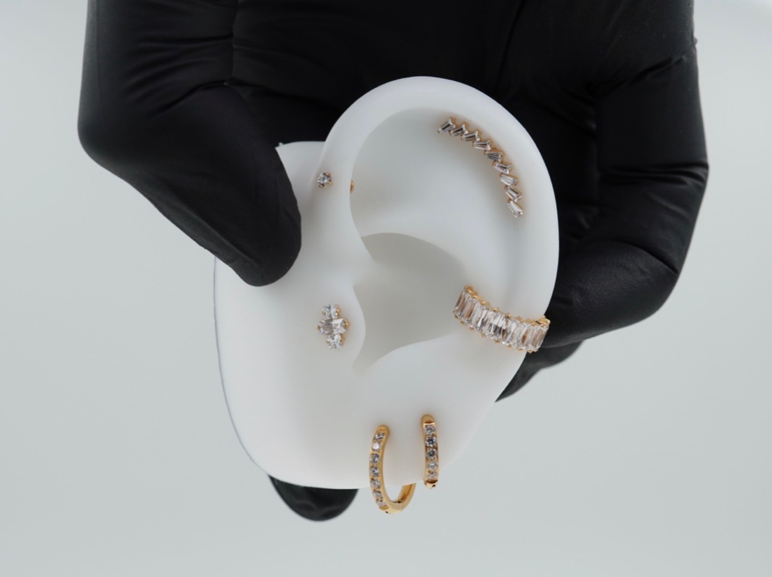 Øre med flere elegante piercinger i gull og stål